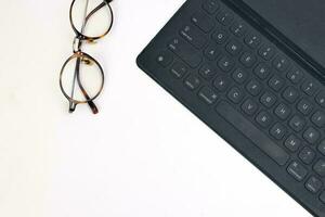 Black computer keyboard eyeglass on white background top view copy text space photo