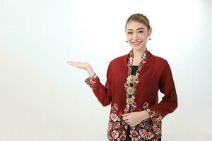 Asian woman traditional red maroon kebaya sharong on white background showing display look palm of hand photo