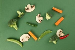chopped sliced diced carrot broccoli white button mushroom red chili on green background photo