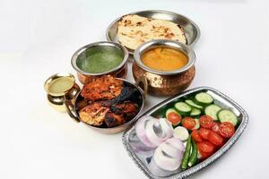Spicy red Chicken grilled tikka tandoori nan bread green spinach curry yogurt sauce dal tomato cucumber onion salad set in metal stainless steel brass copper pot on white background photo
