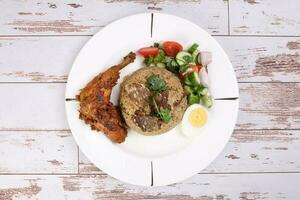 Beef Biryani Tehari with boiled egg coriander leaf garnish chicken curry pot roasted leg tomato cucumber onion chili coriander salad on white plate set over rustic wood background photo