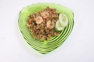 Thai style stair fiend rice with prawn seafood cucumber slice garnish on green glass triangular plate on white background photo