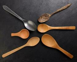 Variety of wooden coconut shell metal spoon laid on black background top flat lay view photo