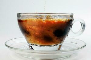 dark Coffee poring white milk dripping splash shadow liquid swirl in glass cup saucer on white background photo