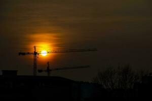 pintoresco, atardecer, sol, nube, cielo ciudad con construcción grúas, foto