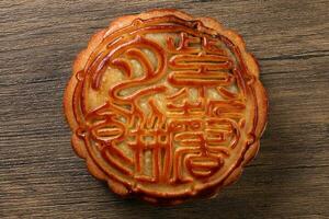 Chinese baked decorated mooncake mid autumn festival square round moon cake filling gift wish offering on bamboo mat over wooden table mini cup photo