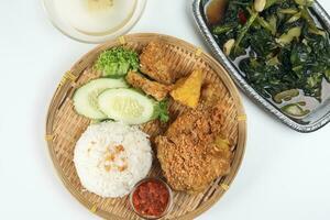 Ayam penyet East Javanese cuisine smashed fried chicken dish with floss sambal slices of cucumbers fried tofu and tempeh Stair fired green Chinese broccoli garlic oyster sauce soup photo