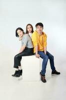 Group of young south east asian mixed race man woman chinese malay sit on box pose white background moody relax fashion students colleagues look at camera photo