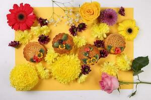 Colorful flower decorated moon cake Chinese mid autumn festival daisy chrysanthemum mum rose baby breath flower red yellow pink purple violet on yellow background photo