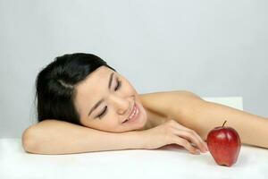 joven hermosa Sureste asiático mujer belleza Moda maquillaje ligero gris blanco antecedentes tendido en su mano sonrisa a rojo manzana foto