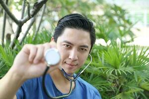 sur este asiático joven malayo chino hombre médico médico sostener estetoscopio a cámara foto