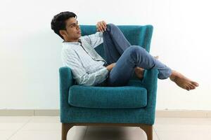 A young south east Asian sit pose look think work study emotion feelings on a blue single sofa. He is adhd and autistic photo