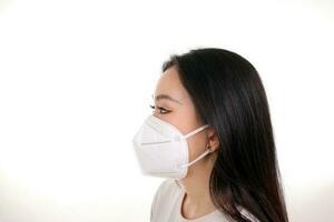 Beautiful young south east Asian woman wearing N95 anti virus bacterial surgical face mask on white background side view photo