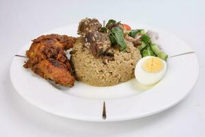 Beef Biryani Tehari with boiled egg coriander leaf garnish chicken curry pot roasted leg tomato cucumber onion chili coriander salad on white plate set over white background photo