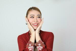 Asian woman traditional red maroon kebaya sharong on white background happy smile surprised hand on cheek photo