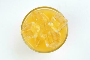 Fresh yellow orange juice in glass with ice cube on white background photo