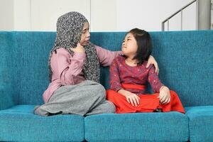 Portrait of southeast Asian malay mother daughter sit on blue sofa talk happy fun laugh. Mother is adhd and child autism autistic photo