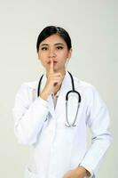 Young Asian female doctor wearing apron stethoscope quite finger hand sign photo