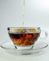 dark Coffee poring white milk dripping splash shadow liquid swirl in glass cup saucer on white background photo