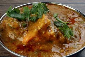 Haleem stew wheat barley lentils mutton goat chicken beef meat bone spice served in a copper brass pot over rustic wood background photo