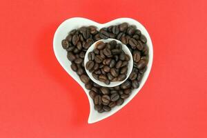 Coffee bean white ceramic cup hart shape plate bowl on red color background photo
