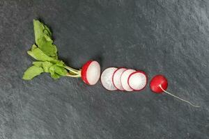 Small red radish on black slate background photo