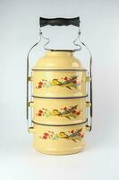 Vintage tin tiffin food tree tier carrier on white background photo