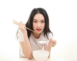 Beautiful young south east Asian woman holding chinese empty chopstick soup spoon bowl utensil pretend acting posing see eat taste feed offer satisfaction yummy white background happy photo