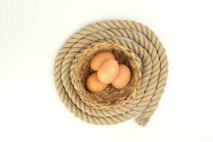 Egg in straw basket jute rope circle around on white background photo