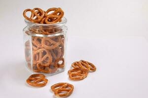 Pretzel cracker in a glass jar pouring dropping on white background photo