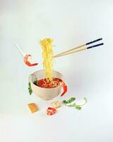 Yellow seafood prawn coriander leaf noodle soup elevated flying suspended in air with soup spoon and chopstick on white background photo