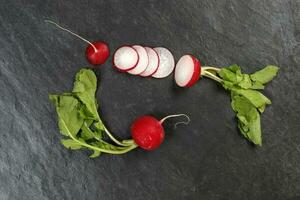 Small red radish on black slate background photo