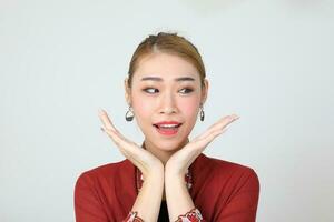 Asian woman traditional red maroon kebaya sharong on white background happy smile surprised hand on cheek photo