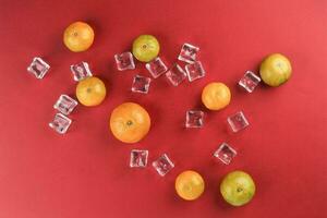 small yellow green mandarin ice cube orange on red colour paper background copy space for text photo
