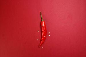 red chilli pepper on red paper background cut pieces seeds photo