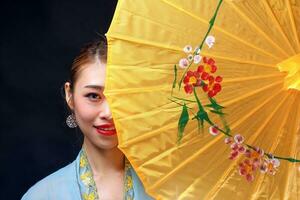 Asian woman in tractional kebaya behind umbrella on black background photo