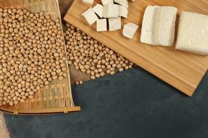 Soyabeans curd tofu soya beans flowing bamboo sieve wooden board on jute black stone slate background photo