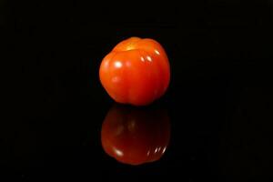 Fresh ripe small shiny red tomato on black background photo