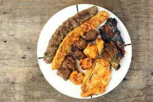 Mixed charcoal grilled platter chicken beef mutton goat meat shish kebab tawook middle east Arab wooden table photo
