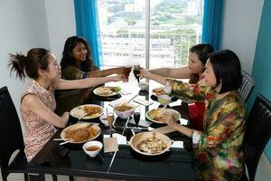 Young southeast asian woman group talk celebrate eating enjoying food rice curry noodle chicken drink cheers on dining table photo