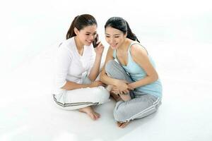 Two beautiful young south east Asian Chinese healthy workout sit on floor talk on phone ease drop gossip on white background photo