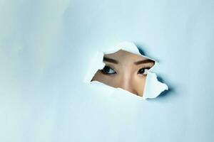 Young beautiful Asian woman expression through torn paper hole photo