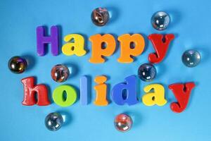 Plastic sign lettering Happy Holiday on blue paper background photo