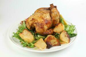 Whole roasted grilled chicken poultry bird with baked potato vegetable salad tomato lemon on white background photo