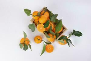 mandarin orange green leaf in wooden box crate top view on white background photo