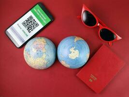 Vaccine passport smartphone app red sunglass world atlas globe map north south pole on red paper background world travel tour vacation photo