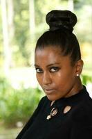 One Asian Indian woman posing serious look towards camera outdoor green park photo