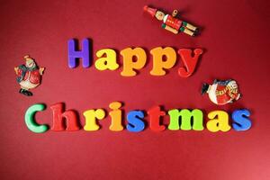 Happy Christmas sign on red paper background color plastic alphabet Santa clause nutcracker ornament photo