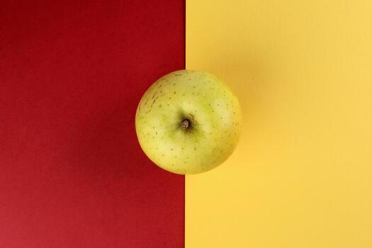 yellow green apple on yellow red colour paper background copy space for text photo