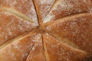 Fresh baked round bread loaf wrapped in checkered kitchen fabric napkin towel over black background photo